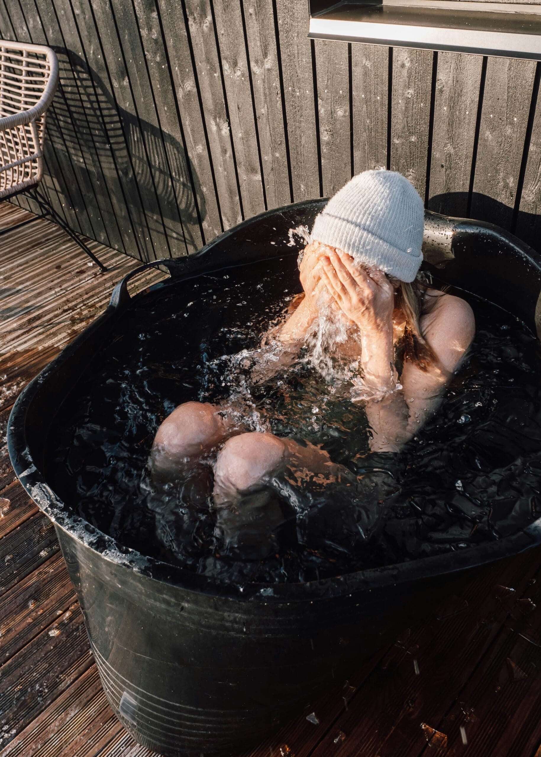 Woman sitting in a cold plunge ice bath outdoors, surrounded by countryside at KG Retreats Rutland