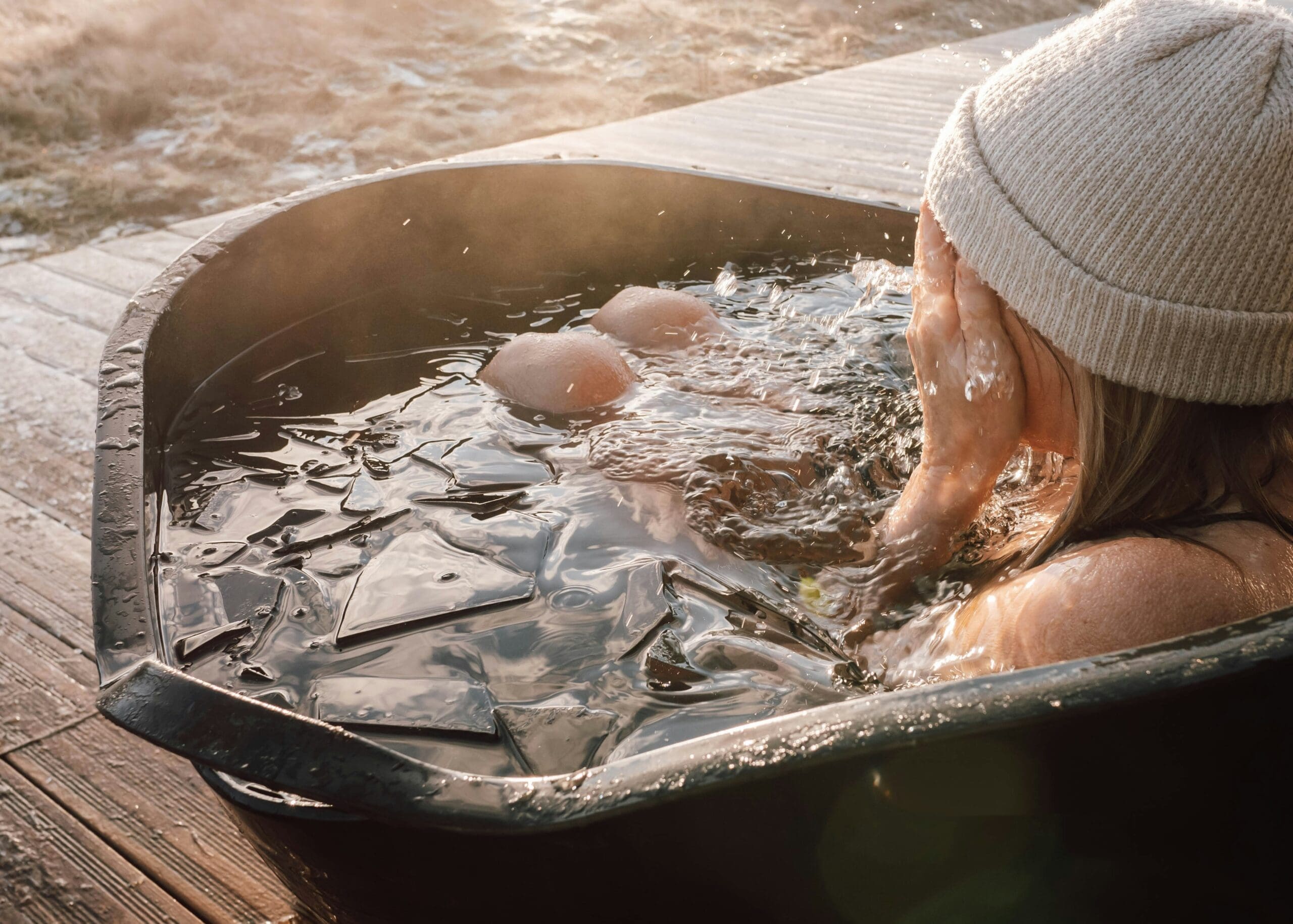 Woman lowering herself into an outdoor ice bath at a rural wellness retreat in Rutland